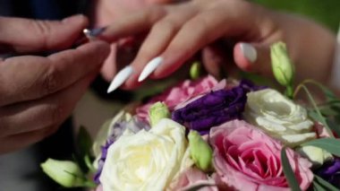 Wedding ceremony. Groom and bride put on wedding rings to each other on summer park background