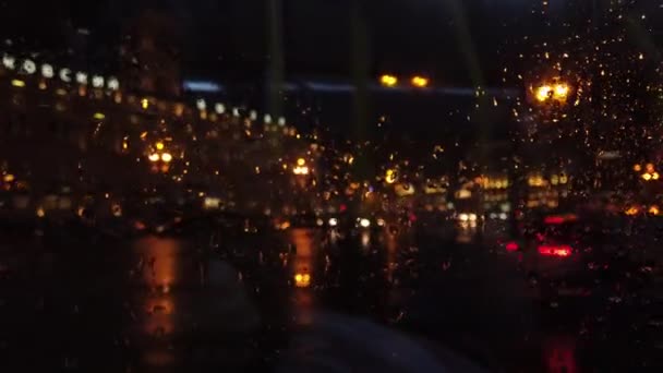 Defocused lights and transport in night city street while it is rainnnig — Stock Video