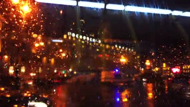 Oskärpa ljus och transport på natten city street medan det regnar — Stockvideo