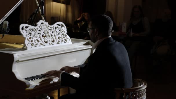 Un pianista de cerca interpretando su propia música en el fondo de la audiencia — Vídeos de Stock