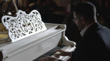 Bir piyanist, seyirci arka planında kendi müziğini icra eder.