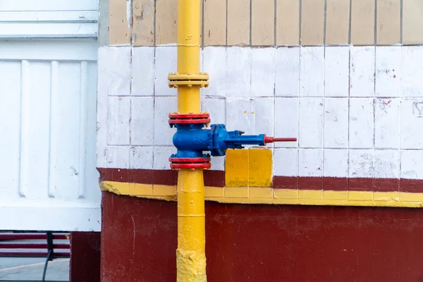 Borularda kırmızı flanşlı mavi kapı vanası, gerekirse doğal gaz dağıtımını ve onu kapatmayı sağlar. Vananın yanındaki boruya bir flanş yerleştirildi. Gaz tedarik sistemi apartmanın yanında bulunuyor.