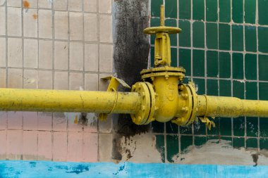 Sarı vana, çarkıfelek, duvarın yanındaki boruda fayanslar. Boru hattı sistemi doğal gaz dağıtımı yapıyor ve gerekirse kapatıyor. Sistem konut binasının yanında yer almaktadır..