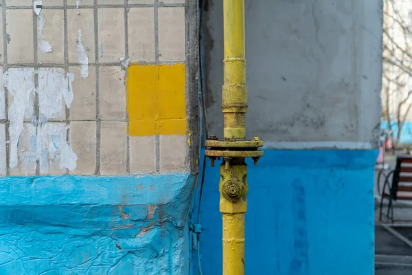 Yellow gas valve with flanges on the pipe near corner of the house. Gas supply system is pumping gas in apartment building and turn off it if necessary. Horizontal orientation image. City background