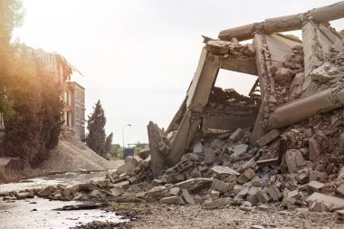 Endüstriyel beton bina deprem tarafından tahrip edildi. Enkaz, toz ve yıkılmış binalarla dolu felaket sahnesi.