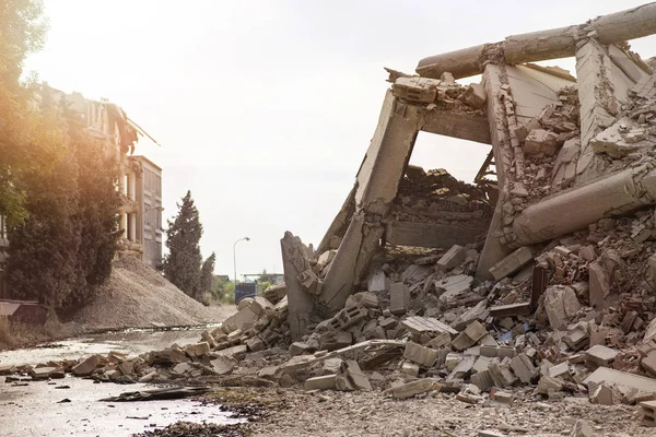 Endüstriyel beton bina deprem tarafından tahrip edildi. Enkaz, toz ve yıkılmış binalarla dolu felaket sahnesi.