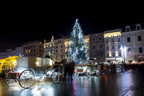 Krakow Polonya 17 Aralık 2017 Market Square Doğu Avrupa ve turistik eski arabayı atları ile ünlü mimarisi ile. Krakow Noel ışık yansımaları ıslak kaldırım ile