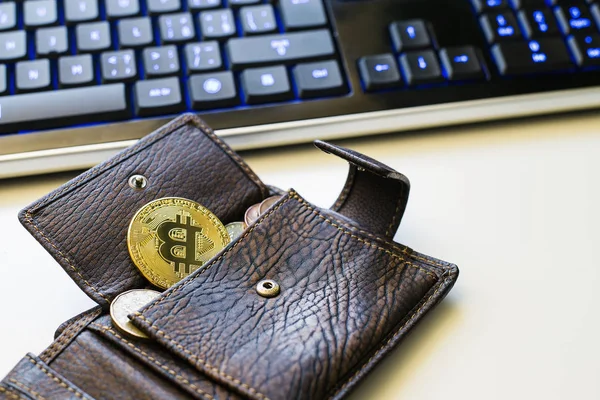 Büyük bir altın Bitcoin ve fiat sikke ve arka planda Mavi ışıklı klavye ile bir açık deri cüzdan detayını. Cryptocurrency online yatırım
