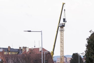 Sarı inşaat vinç araba vinç yardımıyla monte ediliyor. Bunu takmak için crain taksi için ulaşan bir işçi silüeti. İnşaat ekipman againt gri gökyüzü kışın