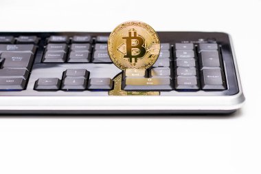 Siyah klavye ve beyaz masa üzerinde duran altın Bitcoin madeni para. Bitir tuþu feryat Bitcoin. Açıklayıcı yazı işleri