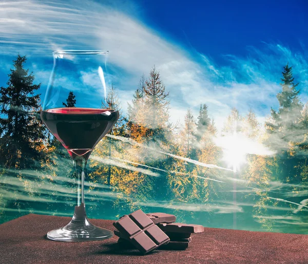 Bicchiere di vino rosso con cioccolato e legno autunnale con paesaggio nuvoloso — Foto Stock