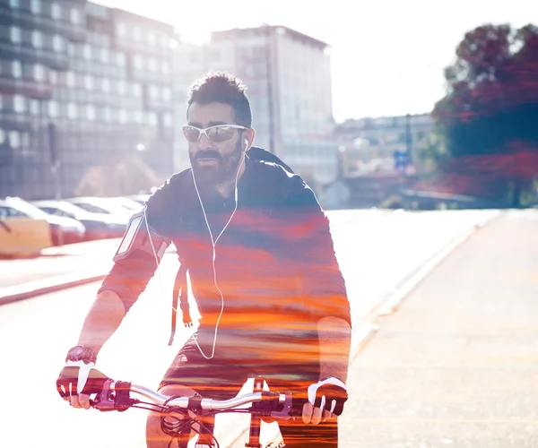 Double exposure of cyclist in the city and colorful sunset — Stock Photo, Image