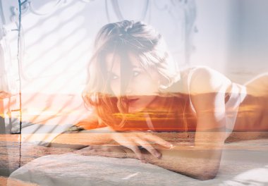 Yatak ve deniz manzarası içinde güzel kadın çift pozlama günbatımı