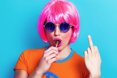 Peruk takıyor ve jest yaparken lolipop yiyen kız pop