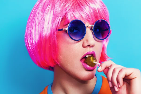 Pop girl wearing pink wig and sunglasses while eating lollipop — Stock Photo, Image