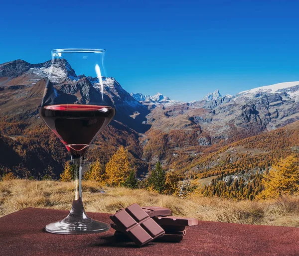 Copa de vino tinto con chocolate y hermoso paisaje montañoso otoñal — Foto de Stock