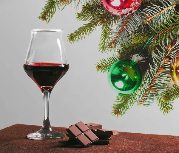 チョコレートやクリスマスの飾りと赤ワインのガラス — ストック写真