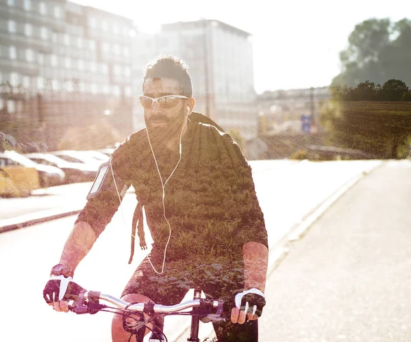 Double exposure of man portrait riding bike and countryside landscape