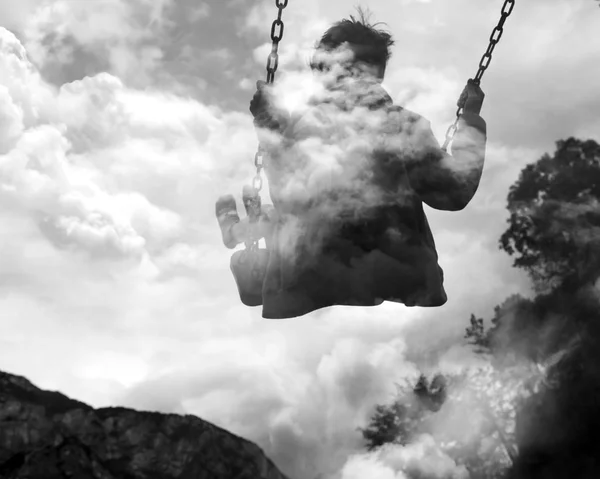 Monochrome double exposure of kid on swing and cloudscape — Stock Photo, Image