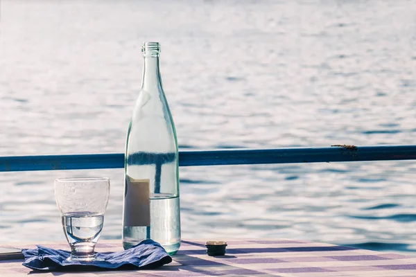 Mesa de restaurante con botella de agua y vidrio cerca del lago Iseo — Foto de Stock
