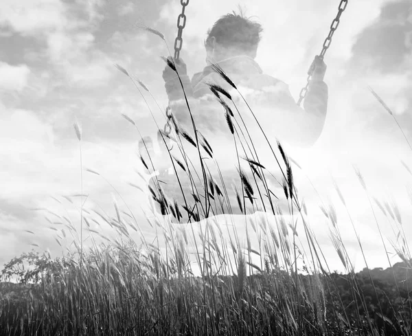 Monochrome double exposure of kid on swing and wheat field — Stock Photo, Image