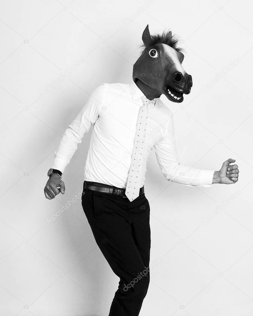 Businessman portrait wearing horse head and running black and white
