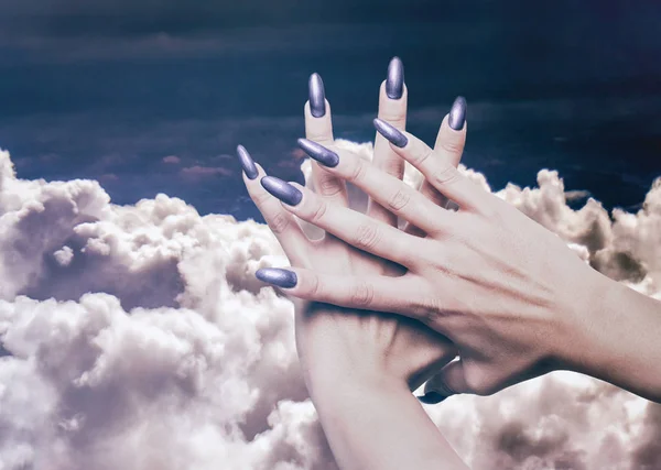 Perfect woman manicure and beautiful cloudscape