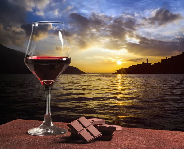 Ποτήρι κόκκινου κρασιού τύπου με σοκολάτα και όμορφο lakescape και cloudscape — Φωτογραφία Αρχείου
