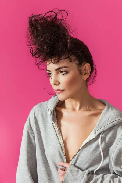 Sensual woman with messy bun wearing grey hoodie and looking aside