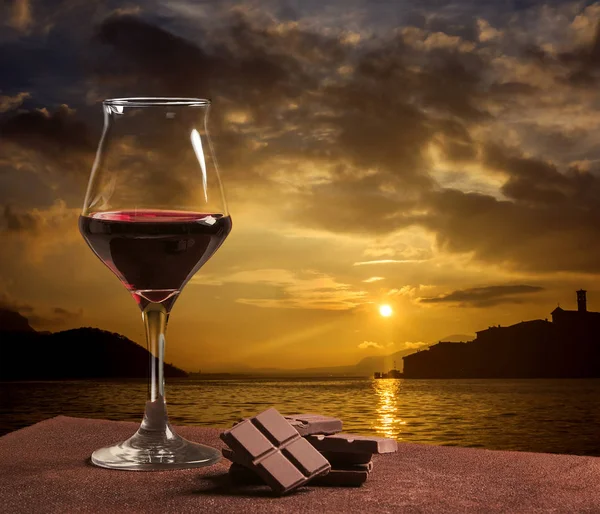 Ποτήρι κόκκινου κρασιού τύπου με σοκολάτα και πανέμορφο ηλιοβασίλεμα στη λίμνη Iseo — Φωτογραφία Αρχείου