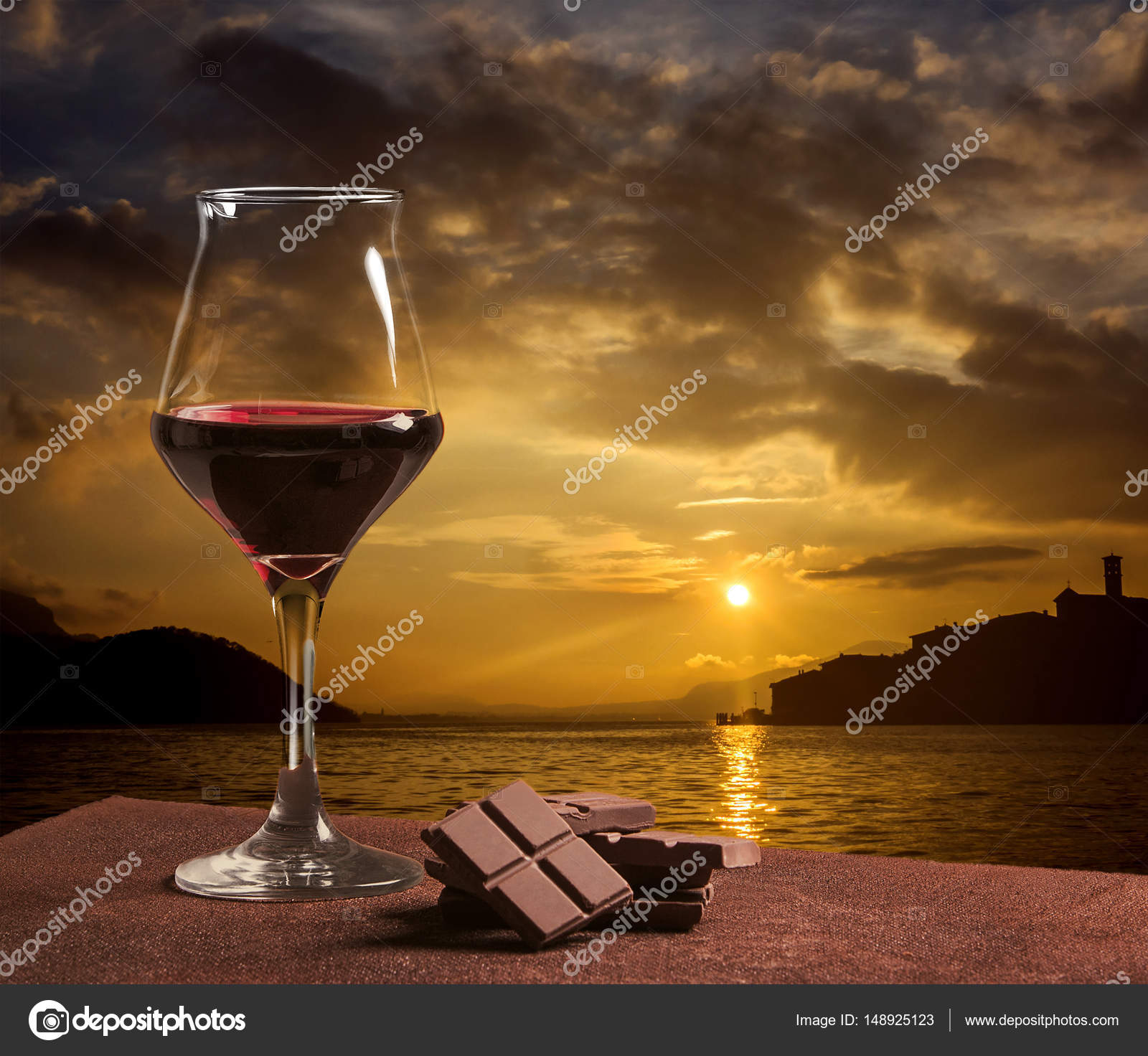 Red wine glass with chocolate and gorgeous sunset on Lake Iseo