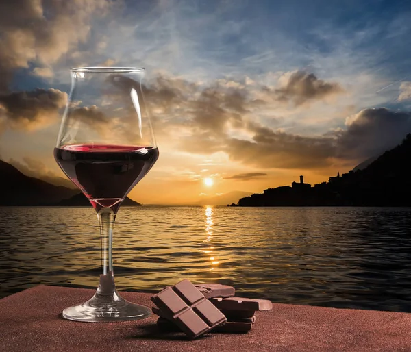 Ποτήρι κόκκινου κρασιού τύπου με σοκολάτα και πανέμορφο ηλιοβασίλεμα cloudscape — Φωτογραφία Αρχείου