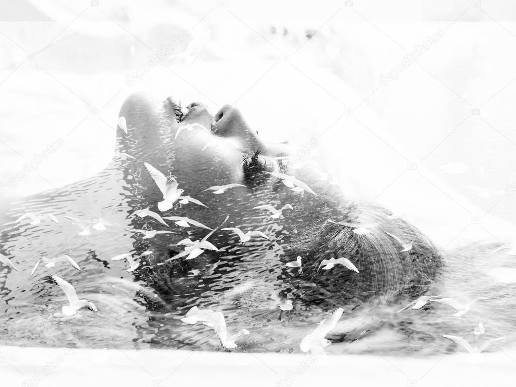 Monochrome double exposure of woman lying in bed and seagulls flying