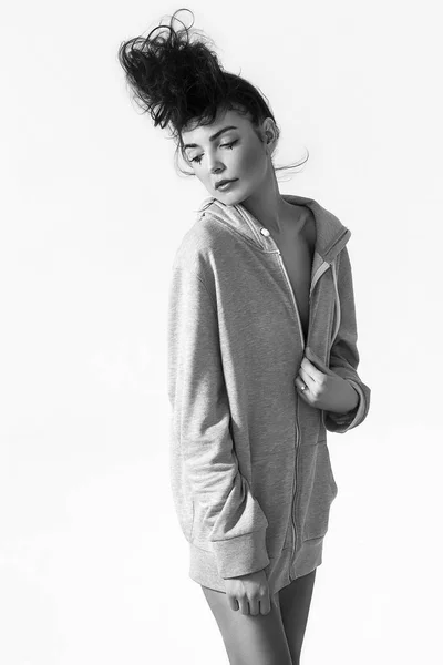 Hermosa mujer con el pelo desordenado con capucha gris y posando, monocromo — Foto de Stock