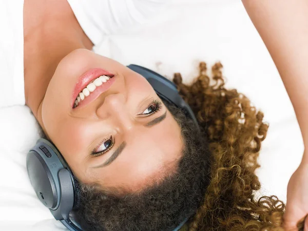 Schöne und ruhige Frau, die auf dem Bett liegt und Musik hört — Stockfoto