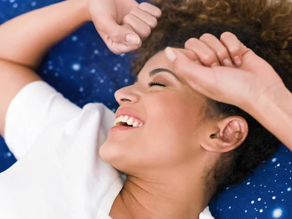 Mulher bonita e feliz que se estende pela manhã, enquanto deitado na cama — Fotografia de Stock