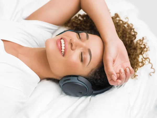 Wunderschönes Frauenporträt liegt auf dem Bett und hört entspannende Musik — Stockfoto