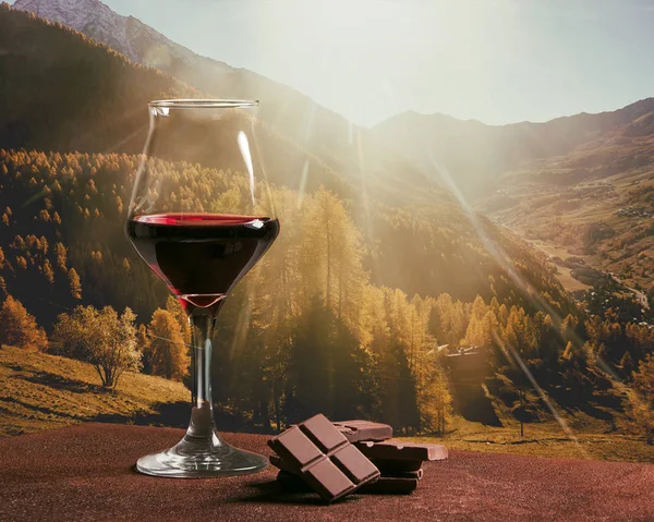 Rotweinglas mit Schokolade und wunderschöner herbstlicher Berglandschaft — Stockfoto