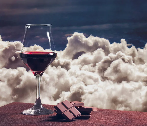 Ποτήρι κόκκινου κρασιού τύπου με σοκολάτα και όμορφη cloudscape — Φωτογραφία Αρχείου