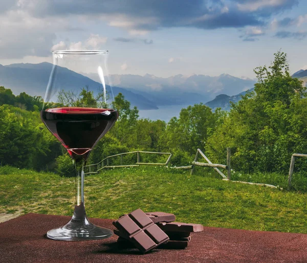 Copa de vino tinto con chocolate y hermoso vislumbre lakescape — Foto de Stock