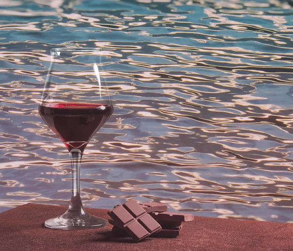 Rotweinglas mit Schokolade und buntem Wasserwellenmuster — Stockfoto