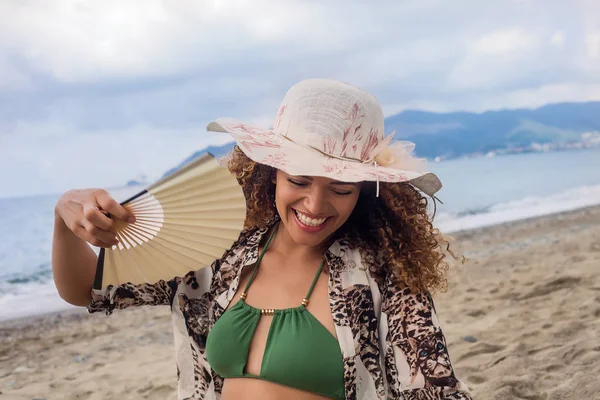 Hermosa y feliz joven mujer sonriendo y sosteniendo ventilador en el b — Foto de Stock