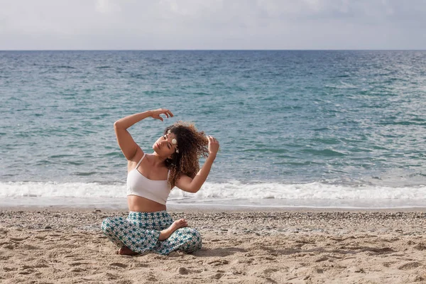 Schöne junge Frau sitzt am Strand und arrangiert ihre Hai — Stockfoto