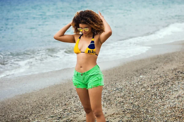 Hermoso retrato de mujer en la playa con gafas de sol, bikini y pantalones cortos — Foto de Stock