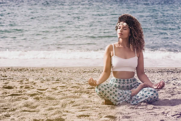 Lovely woman sitting on the beach and meditating — Stock Photo, Image