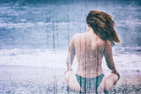 Doppia esposizione della donna seduta sulla spiaggia e modello pioggia — Foto Stock