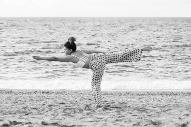 Güzel ve genç birbayan pratik Yoga sahilde, siyah ve beyaz