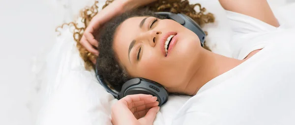 Beautiful woman portrait lying on bed and listening to relaxing music, letterbox — Stock Photo, Image