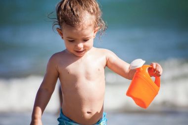Holding ve oyuncak sulama olabilir ile sahilde oynarken sevimli küçük kız