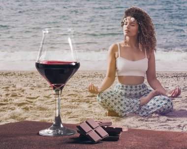Çikolata ve güzel bir kadın portre Sahilde meditasyon ile kırmızı şarap cam